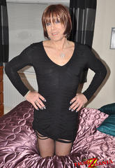 A horny looking shemale waits on a satin sheet covered bed